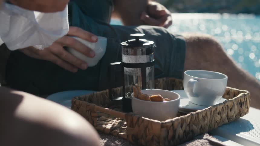 Two people on a yacht next to a breakfast with a coffee