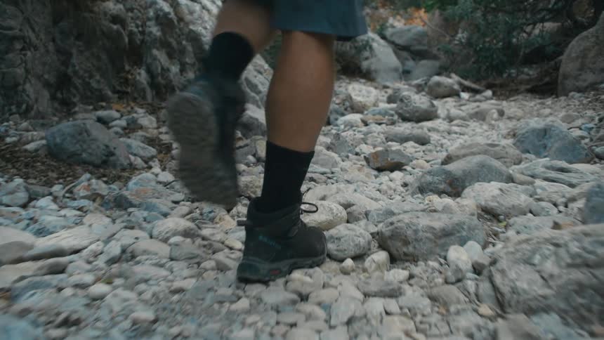 Person in boots walking across rocks on a trail
