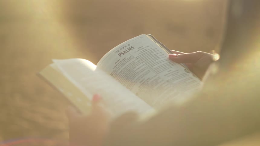 Female reading chapter in bible on psalms outdoors