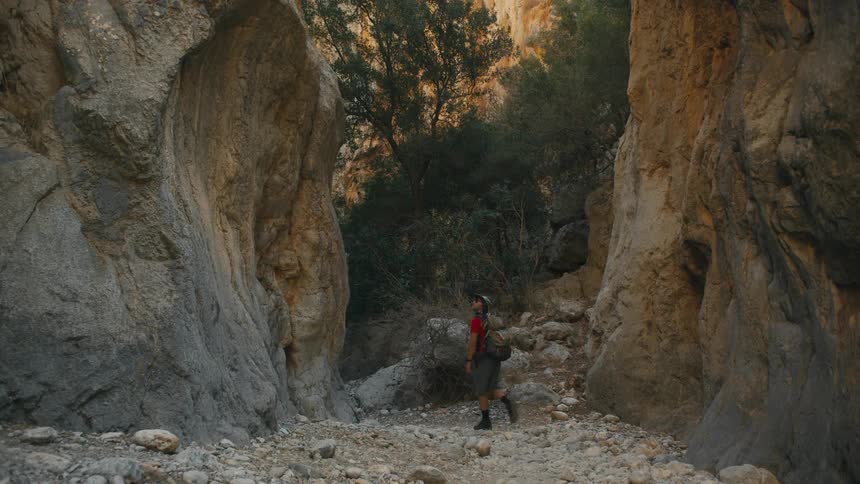 Backpacker hikes into a narrow canyon over rock strewn ground