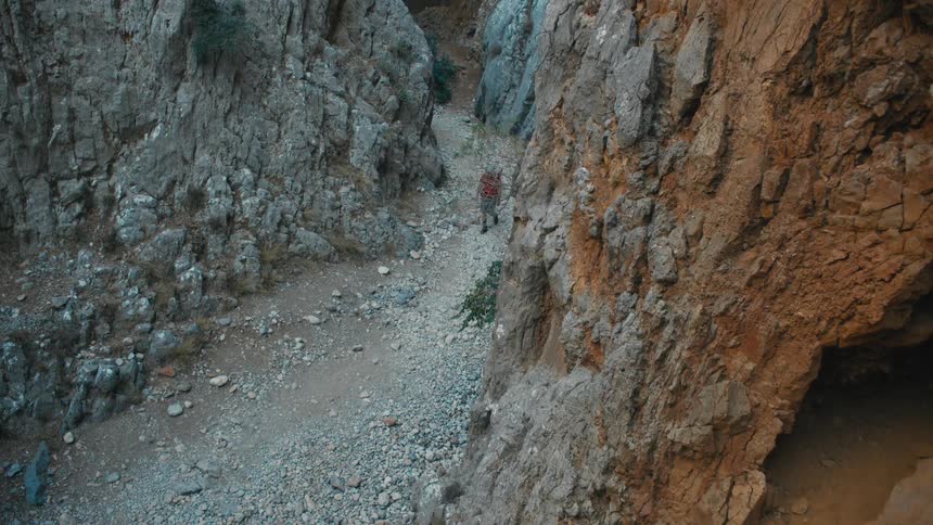 Man hiking between the canyons on a dirt trail