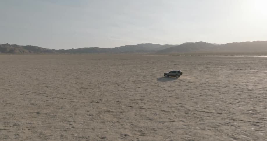 Sports utility vehicle traveling across the desert leaves tracks and kicks up dust
