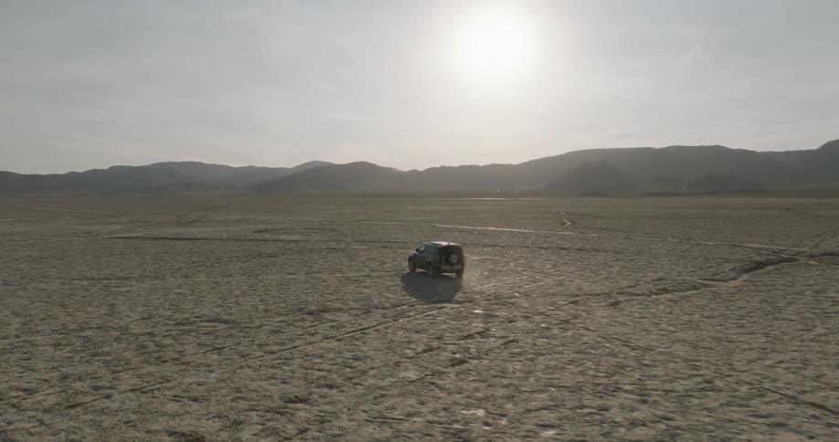 Fourwheel drive car traveling through a desert area with mountains in the background