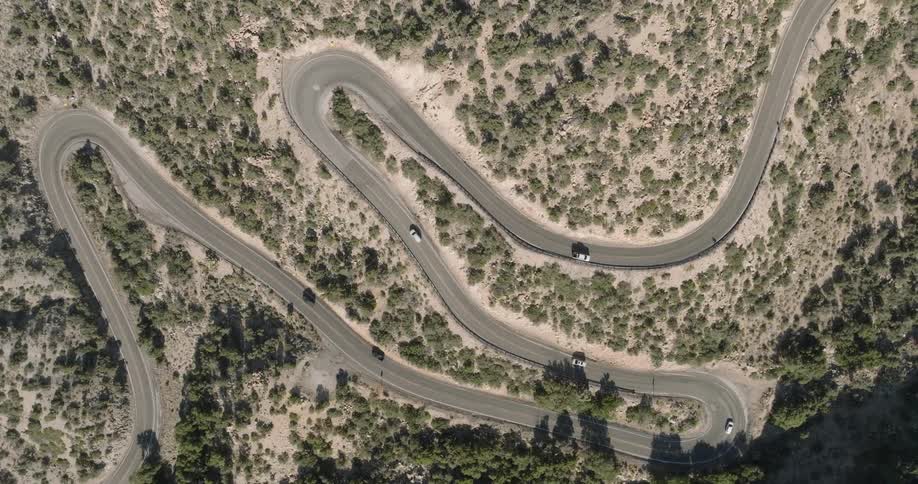 Winding road with vehicle traffic through a mountain with sparse vegetation
