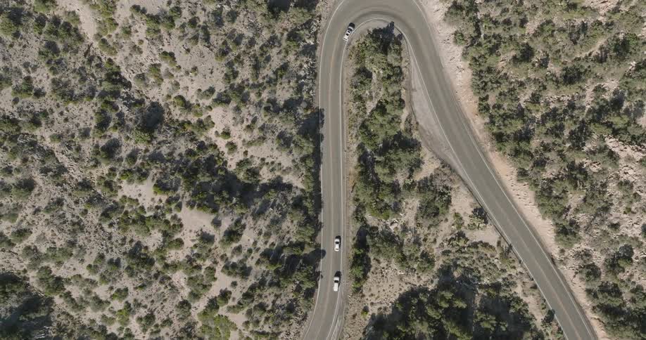 The cars are driving on the road in the hills