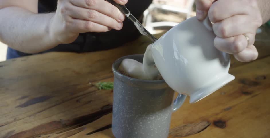 Woman pours cream into the drink