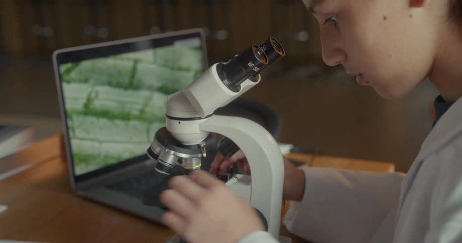Close up of a young female scientist inserting a slide on a microscope to view in a lab during daytime