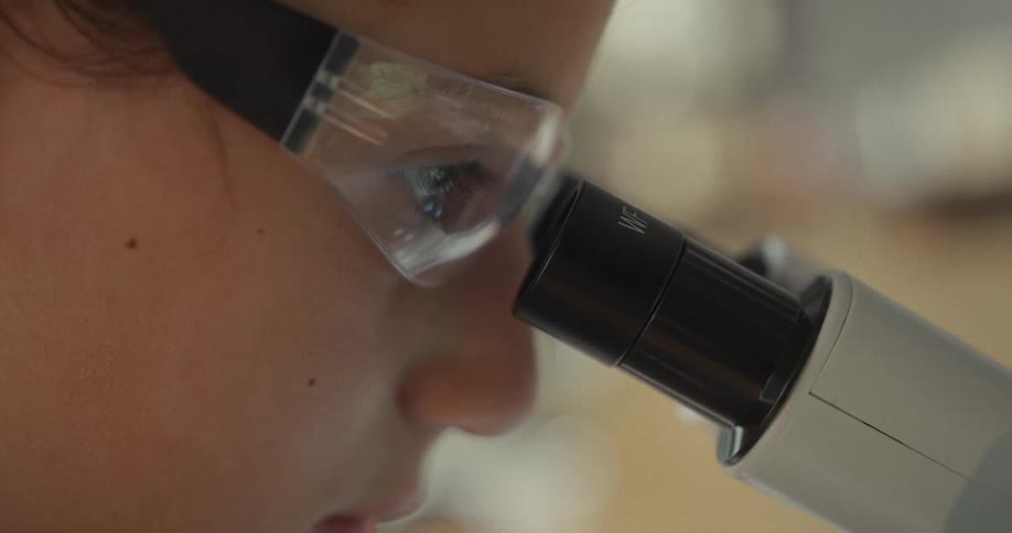 Woman wearing glasses and interacting with microscope