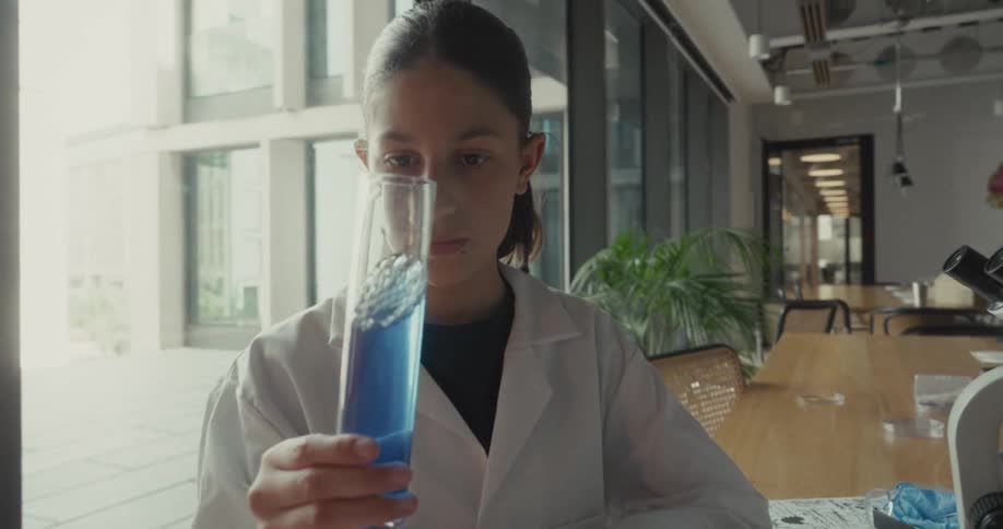 The teenager is mixing a beaker in the lab