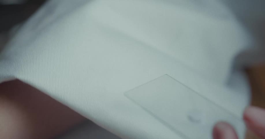 A scientist uses a dropper to put liquid on the microscope slide