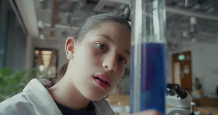Girl holding a laboratory test tube with a blue liquid