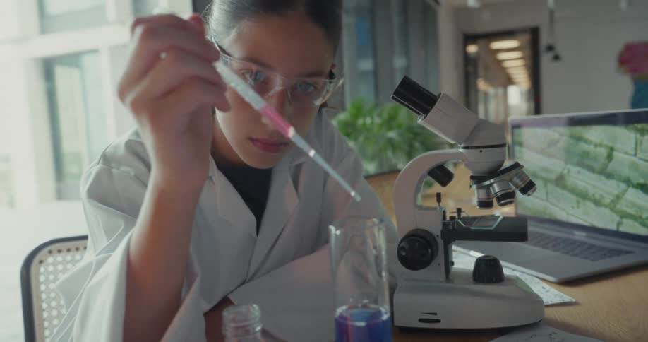 Teenager performing a chemical composition with test tubes and an open laptop next to it