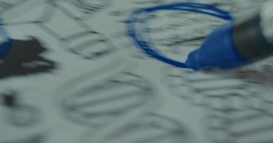 A person circles words on the paper with a blue marker