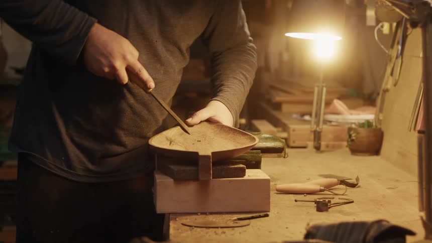 Person in a lowlight indoor environment sculpting an object