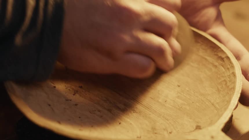 A carpenter is smoothing out a piece of wood removing rough sections to make it smooth