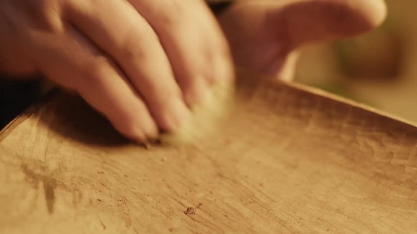 A carpenter is smoothing out a piece of wood removing rough sections to make it smooth