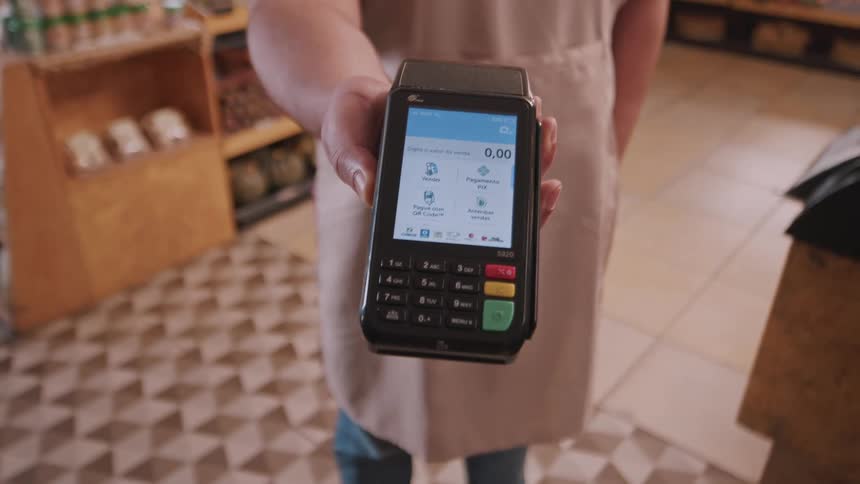 Worker in a store holds out a credit card machine