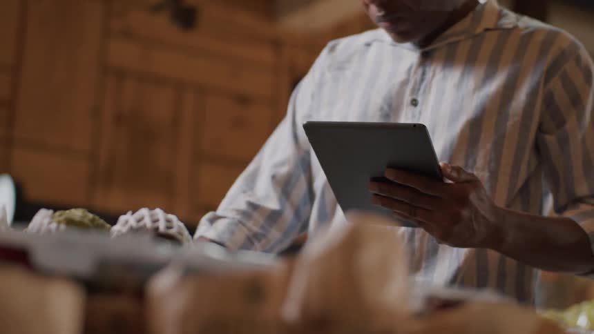 Man in striped shirt uses a tablet while looking at products in a market