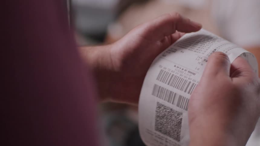 A woman is going through a receipt inside a store after shopping