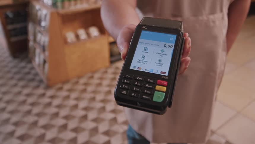 A person holds out a payment terminal for a customer to make a transaction