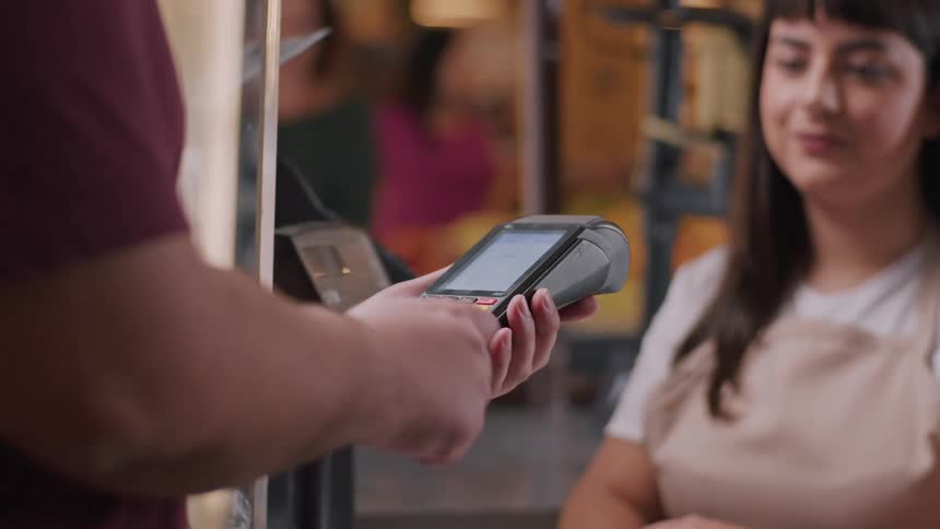 A customer pays using a card machine at a counter