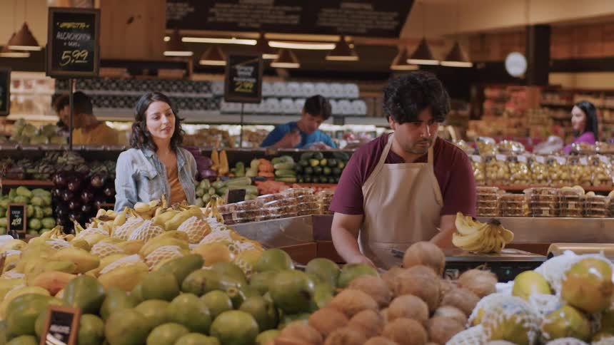 Woman picking up a banana at a grocery store