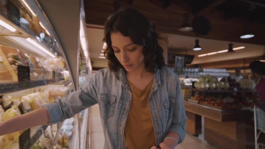 Woman picking up products from a supermarket shelf