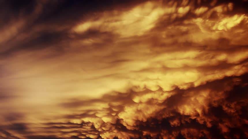 Mammatus clouds spread across the sky with golden hues and deep shadows