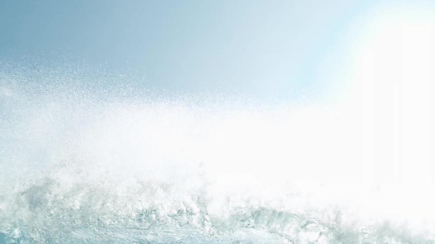 Breaking wave obscures the sky allowing bright sunlight to shine through its water
