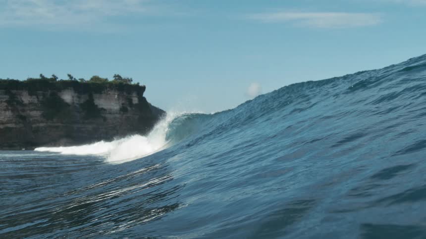 Landscape of a wave breaking in the ocean and the coast in the background