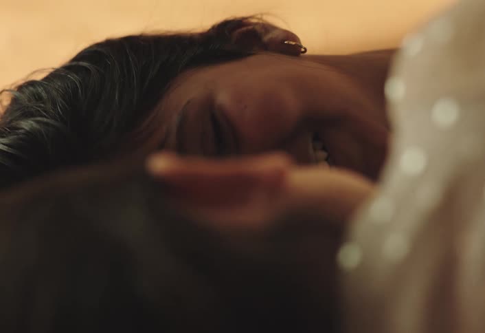 A closeup shot shows a woman with dark hair lying down possibly resting or sleeping her eyes are closed and theres a peaceful expression on her face with soft lighting highlighting her features