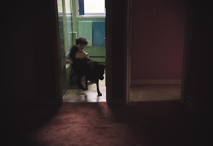 A kid walks out of the bathroom following a dog that is walking out ahead