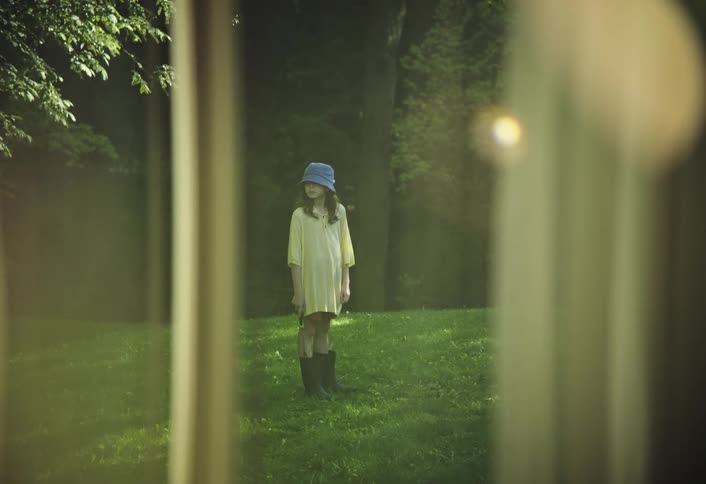 A girl is standing outside the window on the green lawn