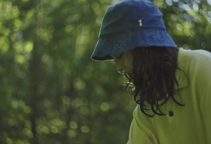 Child wearing a blue hat plays with water in a backyard