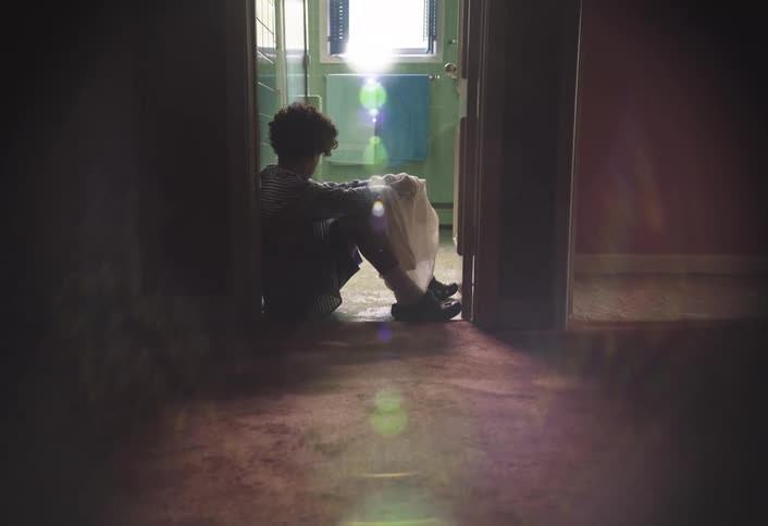 The boy is sitting in the doorway