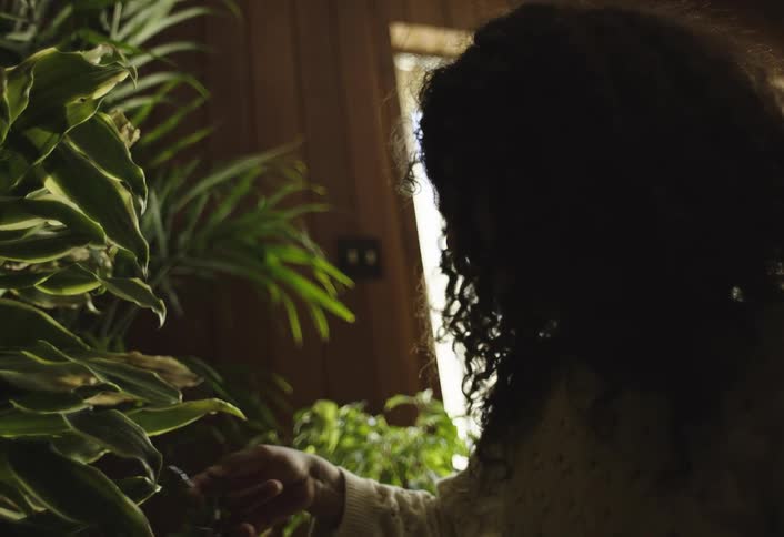 Curly haired girl watering plants indoors