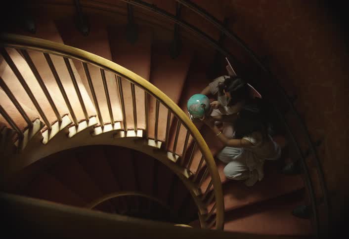 Two ladies are on a curved staircase playing with a globe of the earth