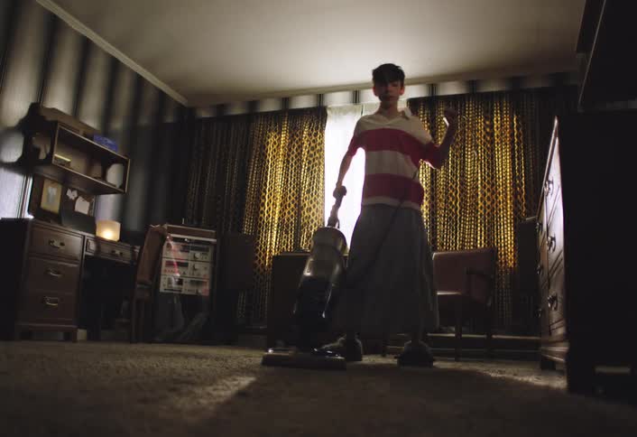 Boy vacuuming the carpet in a living room