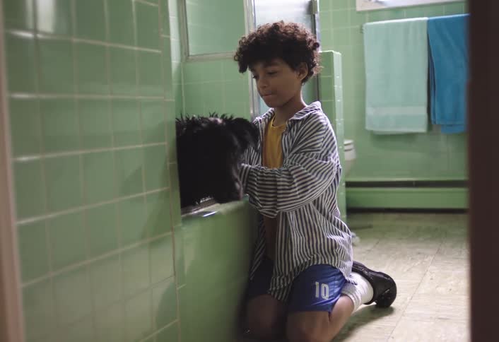 The boy is washing his dog in the bathroom at home