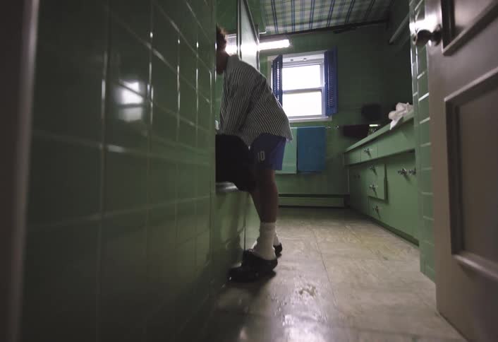 Boy stands next to the tub in the bathroom giving his dog a bath