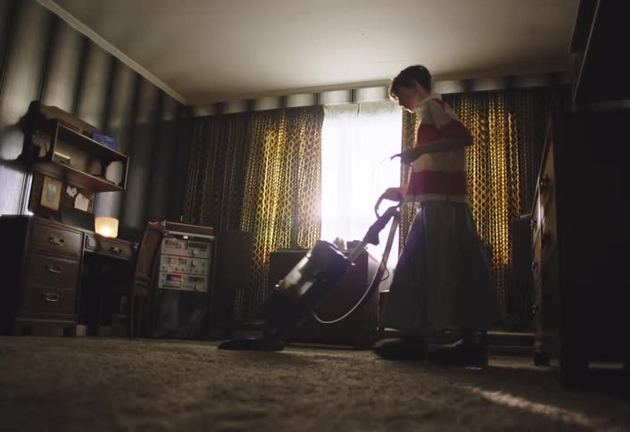 Boy vacuuming the carpet in a room of the house