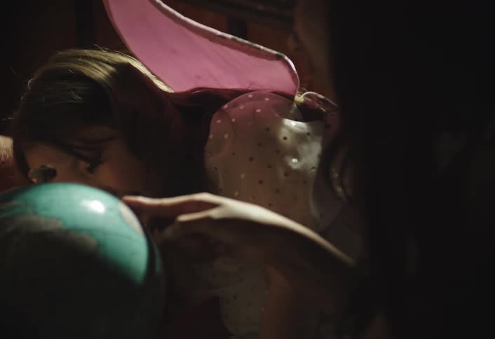 Two girls one of them wearing fairy wings play with a globe atlas