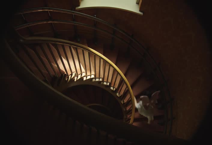Two young girls in costumes run up a long winding staircase