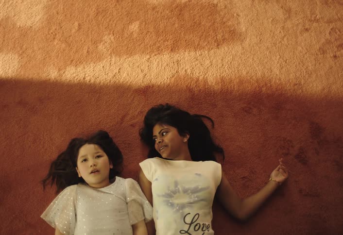 A mother and daughter fall backward in relief onto a brown carpet