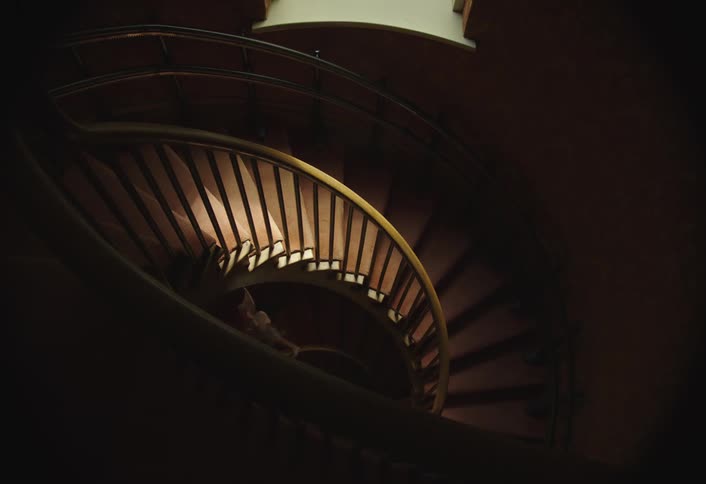 Two girls one of them wearing fairy wings walk down a spiral staircase