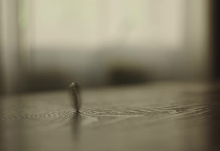 Silver coin spinning on a wood table indoors