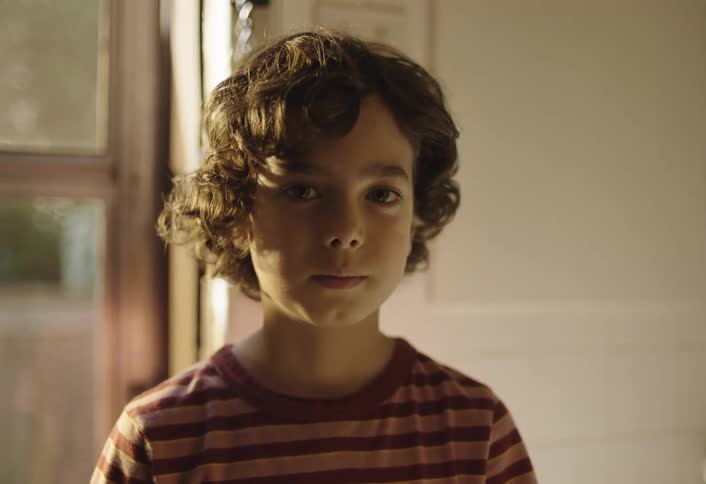 Boy near a window turns his head to look straight ahead