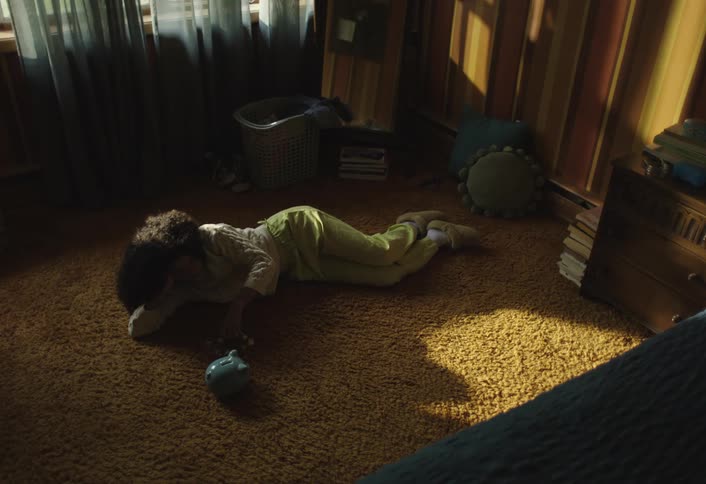 Child lies on floor putting coins in piggy bank