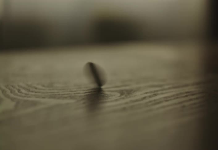 Hand spinning a coin on top of a wooden table