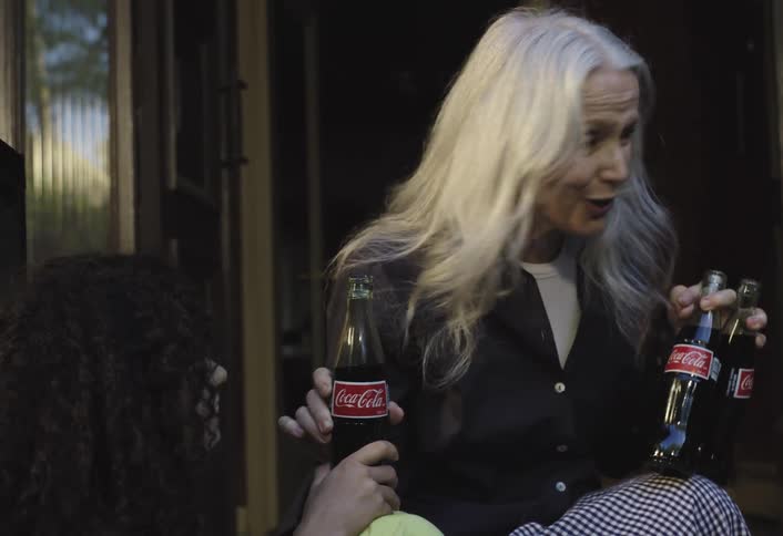 A woman exits the home and hands the children sodas